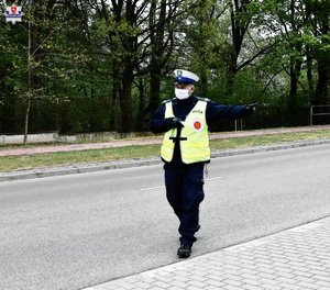 policjant na drodze wskazuje ręką miejsce zatrzymania pojazdu