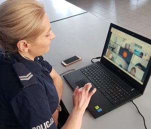 policjantka przed laptopem w trakcie lekcji z uczniami, na ekranie uczniowie