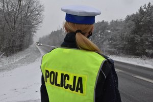 policjantka stojąca tyłem przy zaśnieżonej drodze